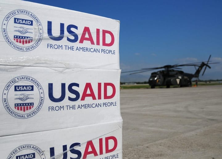 USAID crates of supplies with helicopter in background. Image from USAID's Flickr. CC: BY-SA 2.0.